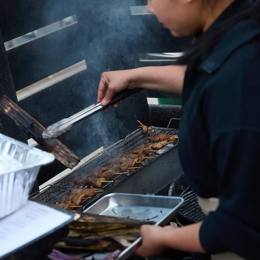 Grilling skewers over open flame with smoke rising